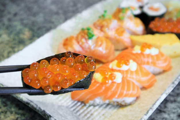 Rouleau de sushi sashimi au saumon serti de baguettes sur la plaque Cuisine japonaise