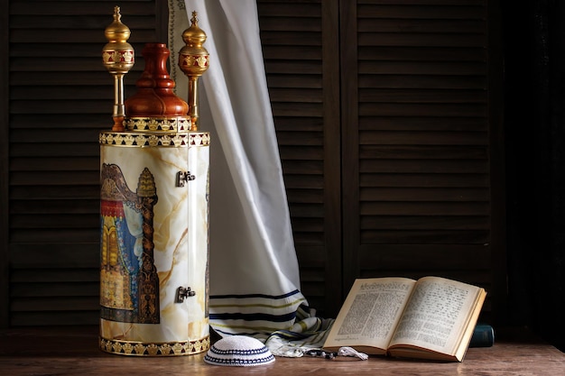 Rouleau de la Torah avec un châle de prière, un tallit et une kippa sur un fond sombre