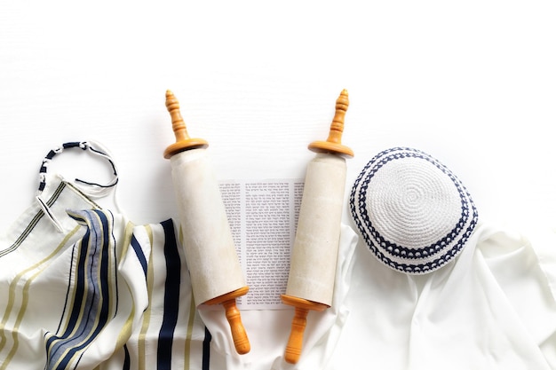 Photo rouleau de la torah avec un pointeur, un châle de prière, un tallit et une kippa sur un fond clair