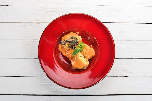 Rouleaux de chou à la sauce tomate dans une assiette rouge Sur une table en bois Vue de dessus Espace de copie