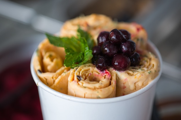 Rouleaux de crème glacée sautés au plat de congélation. Glace roulée, dessert à la crème glacée à la main. Machine à crème glacée frite avec casserole réfrigérée en acier.