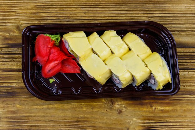 Rouleaux de fromage à sushi dans une boîte en plastique sur une table en bois Vue de dessus