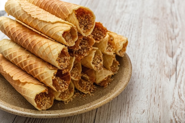 Rouleaux de gaufrettes à la crème sur une assiette. Pâtisserie maison. Fond en bois. photo