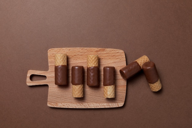 Rouleaux de gaufrettes croustillantes à moitié enrobés de chocolat au lait sur un plateau de service