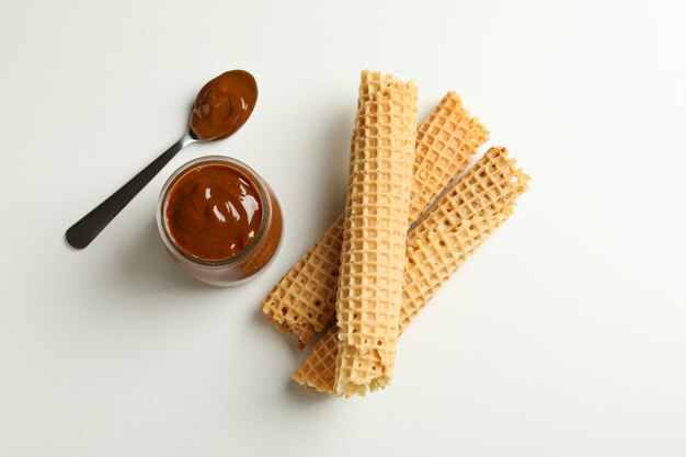 Rouleaux de gaufrettes et pot de lait condensé sur fond blanc