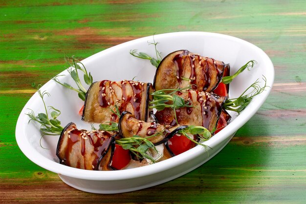 Rouleaux de légumes d'aubergine avec sauce unagi Sur un fond en bois coloré Plat végétarien