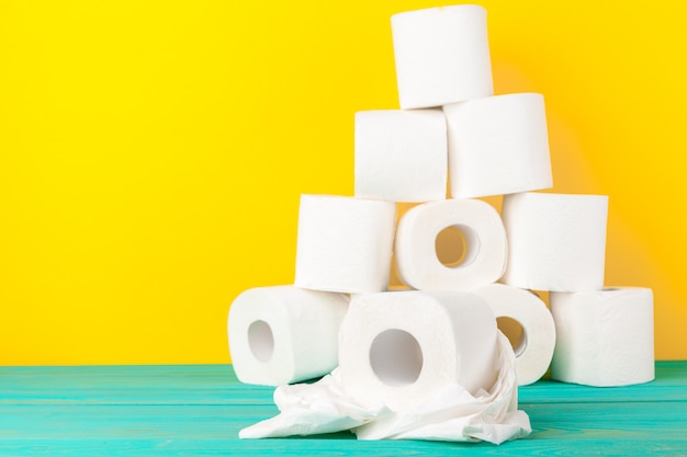 Rouleaux de papier hygiénique empilés sur du papier jaune