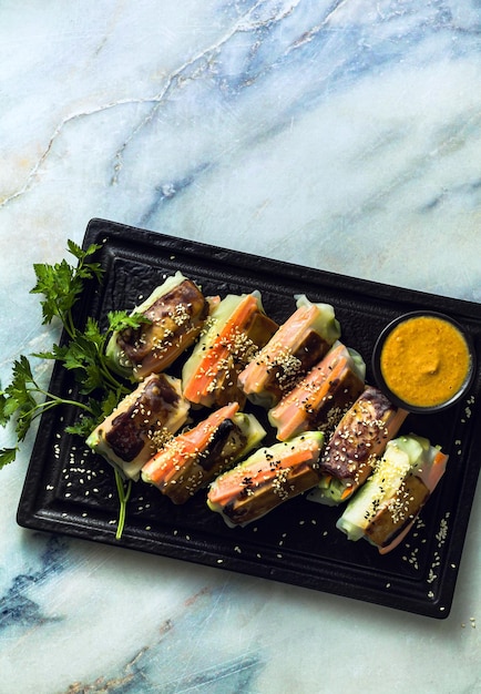 Rouleaux de papier de riz de printemps végétaliens sains avec fromage de tofu frit et légumes frais et sauce aux amandes