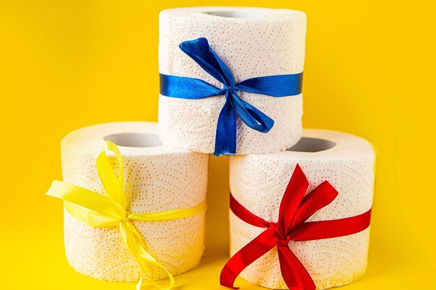 rouleaux de papier toilette enveloppés dans des nœuds de cadeau sur un fond jaune vif concept Covid-19