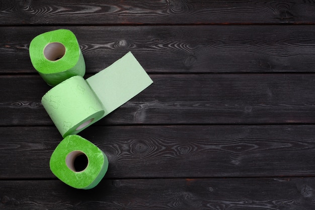 Rouleaux de papier toilette vert sur table en bois noir