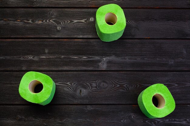 Rouleaux de papier toilette vert sur table en bois noir