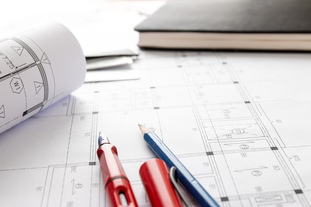 Rouleaux de plans d'architecture et de plans de maison sur la table et outils de dessin d'architecte.