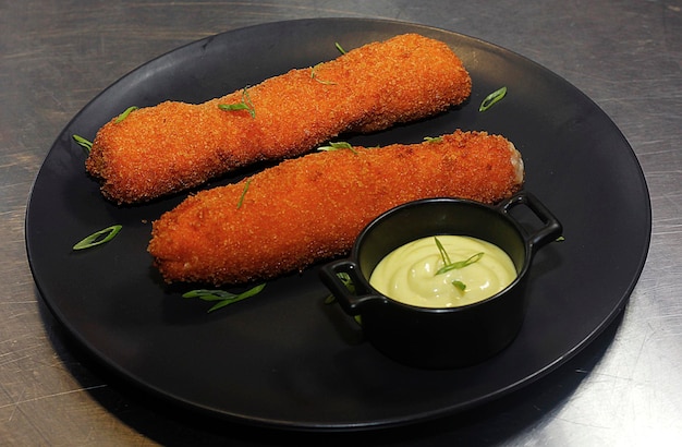 Rouleaux de printemps croustillants remplis de poulet et de fromage servis avec sauce dans une assiette noire