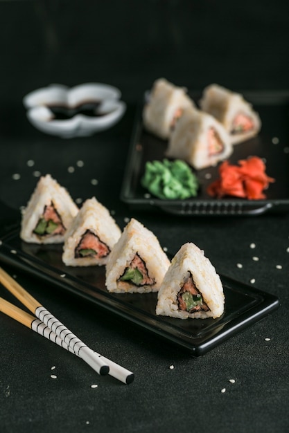 Rouleaux de quinoa surimi japonais au gingembre mariné et sauce wasabi sur une plaque noire avec des baguettes