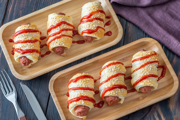 Rouleaux de saucisse sur le plateau en bois