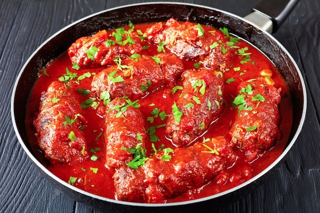 rouleaux de steak de bœuf farcis de prosciutto tranché, de parmesan râpé et de persil, cuits avec sauce marinara dans une poêle