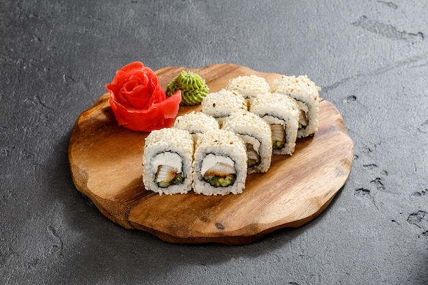 Rouleaux de sushi sur une assiette en bois servis avec du wasabi et du gingembre