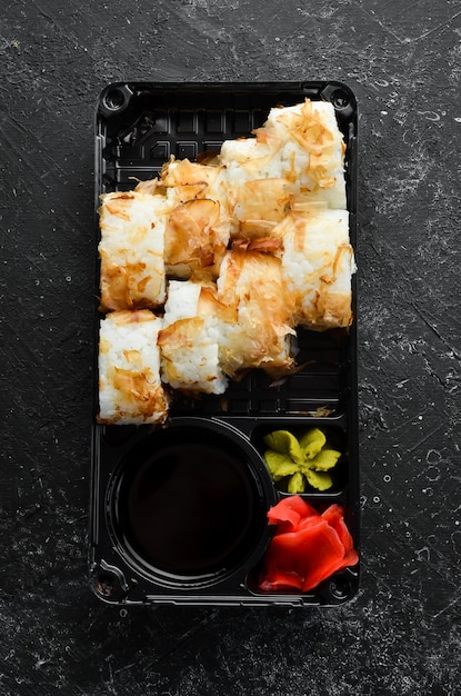 Rouleaux de sushi au fromage et chips de thon wasabi et sauce soja dans une boîte en plastique Vue de dessus