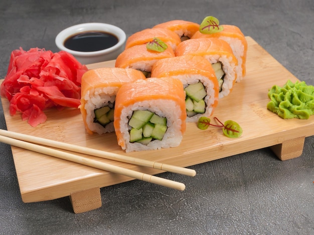 Rouleaux de sushi au saumon et concombre sur une planche de bois