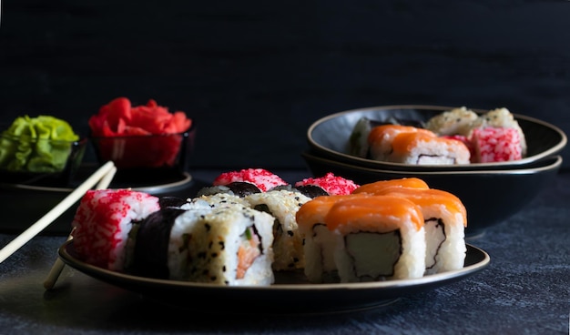 Rouleaux de sushi avec des baguettes de bambou au gingembre wasabi sur fond sombre Vue latérale