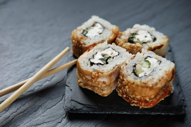 Rouleaux de sushi avec des baguettes sur fond sombre