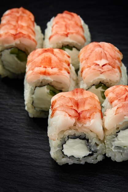 Rouleaux de sushi californiens avec fromage à la crème de crabe des neiges concombre graines de sésame et caviar de masago isolés sur fond noir avec réflexion Cuisine orientale japonaise