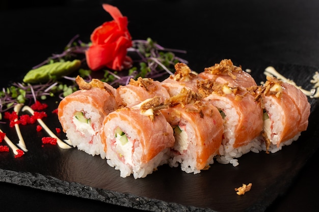 Rouleaux de sushi avec concombre, crevettes, chair de crabe, saumon flammé et fromage à la crème à l'intérieur