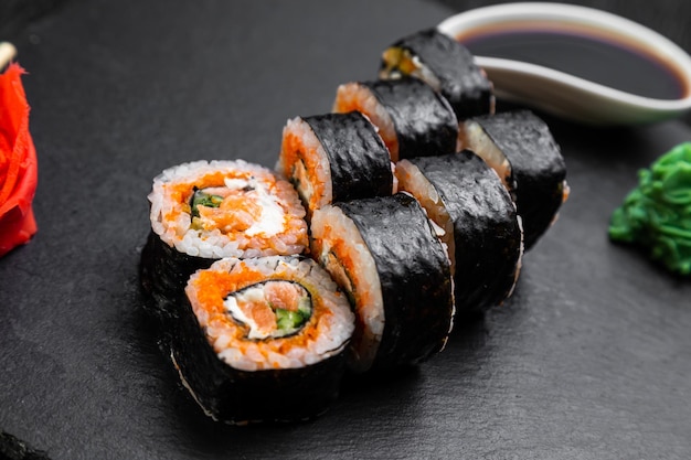 Rouleaux de sushi disposés sur un fond sombre décoré de feuilles de bambou et de baguettes