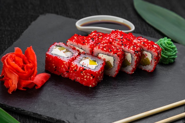 Rouleaux de sushi disposés sur un fond sombre décoré de feuilles de bambou et de baguettes