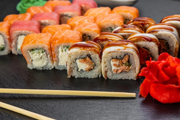 Rouleaux de sushi disposés sur un fond sombre décoré de feuilles de bambou et de baguettes