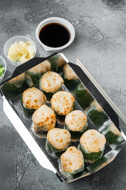 Rouleaux de sushi à emporter dans des conteneurs, rouleaux de philadelphie et rouleaux de crevettes au four, sur fond de pierre grise