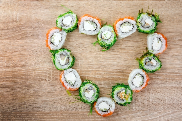 Des rouleaux de sushi étaient posés sur la table en forme de cœur. Ensemble de vacances pour la Saint-Valentin. Vue de dessus.