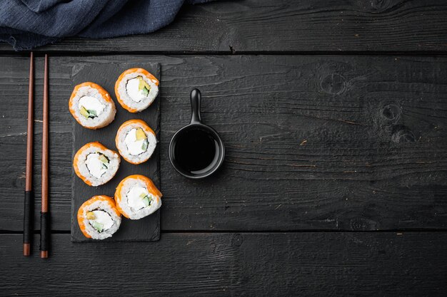 Rouleaux de sushi frais avec wasabi et gingembre, sur table en bois noir