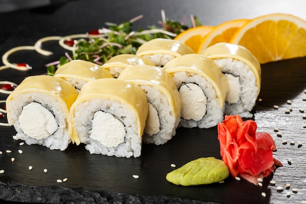 Rouleaux de sushi avec fromage fondu, cheddar, fromage américain et fromage à la crème à l'intérieur sur fond noir