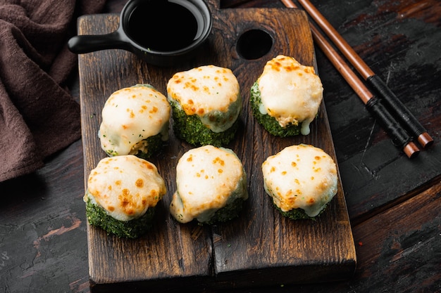 Rouleaux de sushi japonais nommés Baked Ebi avec du wasabi et du poisson au saumon, sur fond de table en bois ancien