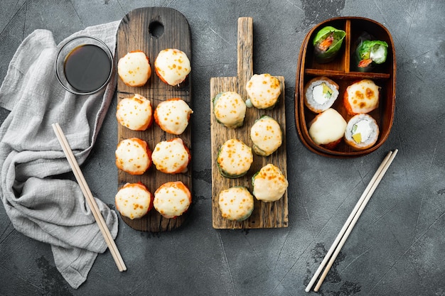 Rouleaux De Sushi Maki Cuits Au Four Avec Saumon, Crabe, Concombre, Avocat, œufs De Poisson Volant Et Sauce épicée, Sur Fond De Pierre Grise, Vue De Dessus à Plat