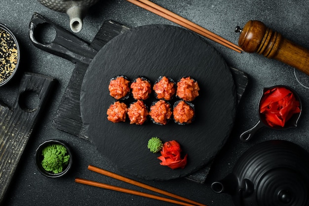 Des rouleaux de sushi noirs appétissants avec du poisson servis sur une planche noire Sushi sur une table