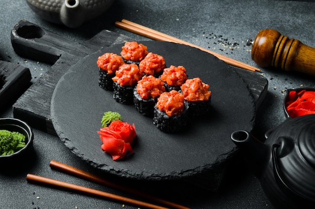 Rouleaux de sushi noirs appétissants avec du poisson servis sur un tableau noir Sushi posés sur une table