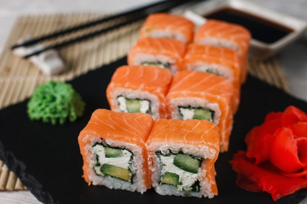 Rouleaux de sushi philadelphie savoureux et frais au gingembre et au wasabi servis sur ardoise noire, gros plan. De délicieux fruits de mer japonais pour les gourmets.