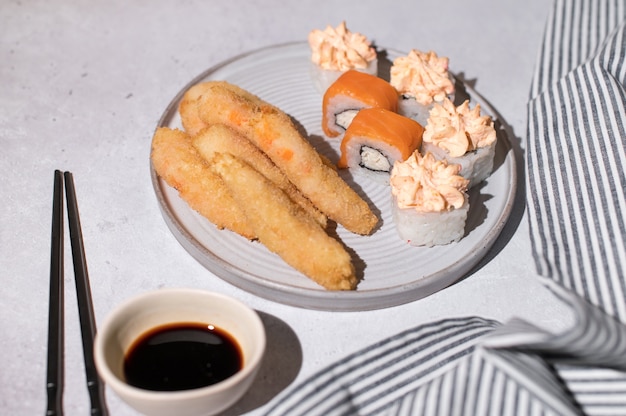 Photo rouleaux de sushi sertis de saumon, crème au fromage et crevettes frites sur plaque grise