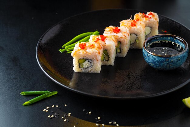 Rouleaux et sushis asiatiques traditionnels avec sauce soja et wasabi servis sur fond sombre