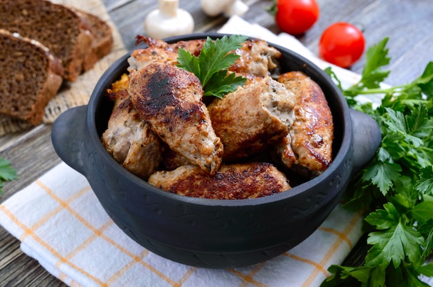 Rouleaux de viande savoureuse aux champignons dans un pot en céramique sur une table en bois