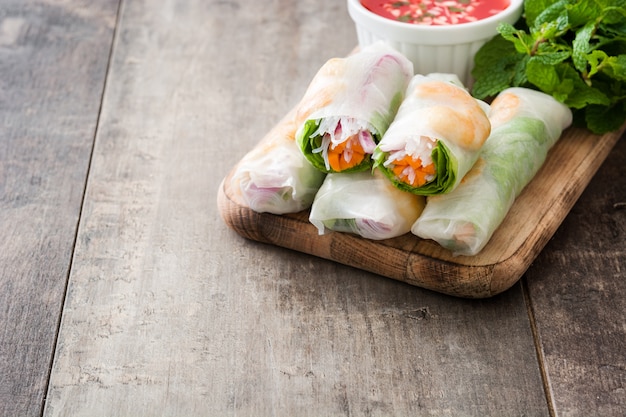 Rouleaux vietnamiens avec légumes, nouilles au riz et crevettes sur l'espace de copie en bois