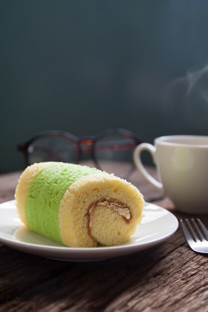 rouler le gâteau avec une boisson chaude sur la table en bois