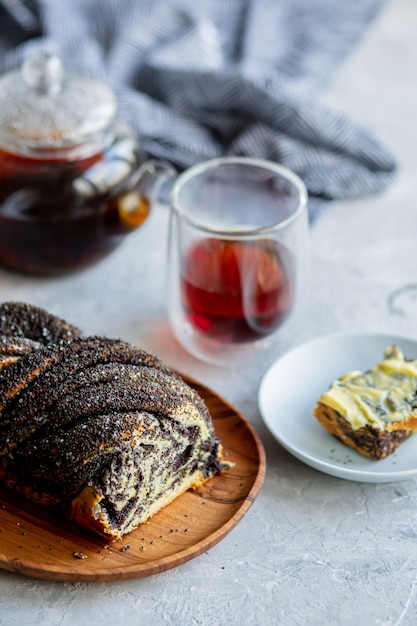 Rouler avec des graines de pavot, du beurre et du thé. Cuisson avec des graines de pavot. Le travail du boulanger. Petits pains avec des graines de pavot et des tartes dans la cuisine. Boulangerie, cuisinez ensemble.