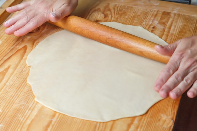 Photo rouler la pâte à gâteau avec un rouleau à pâtisserie en bois