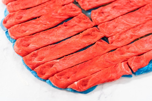 Rouler la pâte à pain rouge et bleu pour cuire des torsades patriotiques à la cannelle.