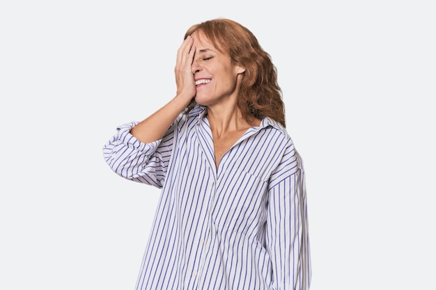 Une rousse d'âge moyen, blanche, dans le studio, riant, heureuse, insouciante, émotion naturelle.