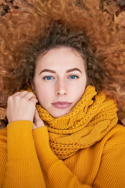 Rousse bouclée belle femme allongée sur les feuilles d'automne