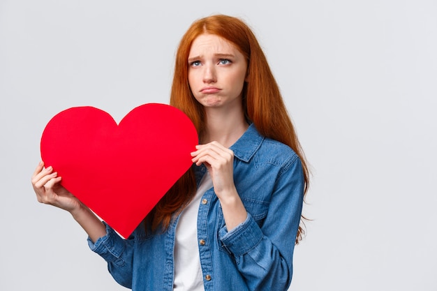 rousse charismatique tenant coeur avec une expression triste